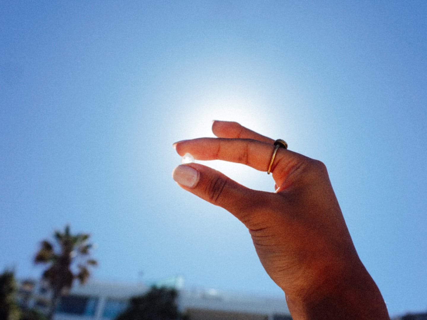 A tear of mastic resin held up against a bright blue sky.